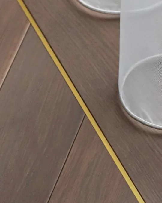 Brushed brass inlay strip set into dark oak herringbone parquet